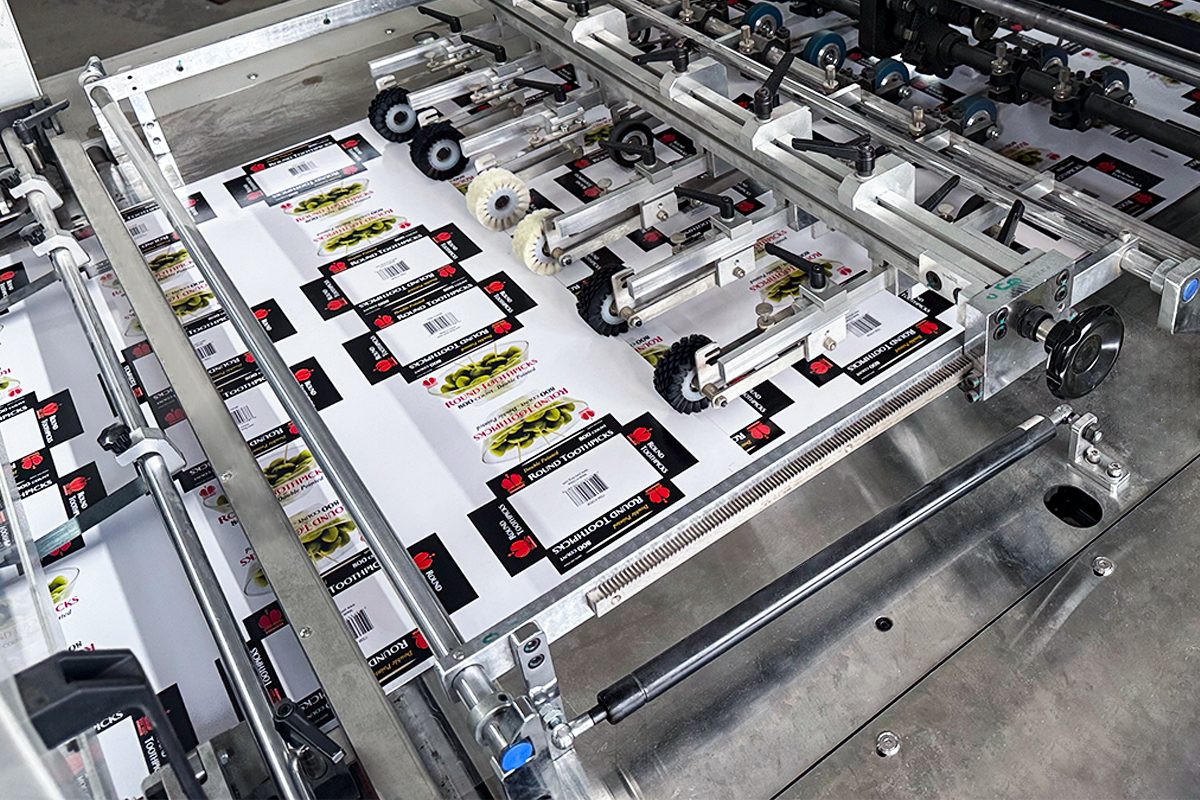Offset printing press feeding printed box sheets in our workshop